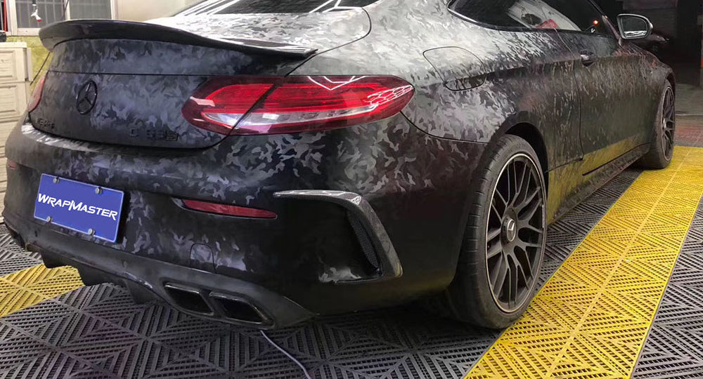 Rear of a Mercedes coupe wrapped in black 3D Ghost Camouflage vinyl, showing the tone on tone camo pattern across the trunk, bumper and rear quarter