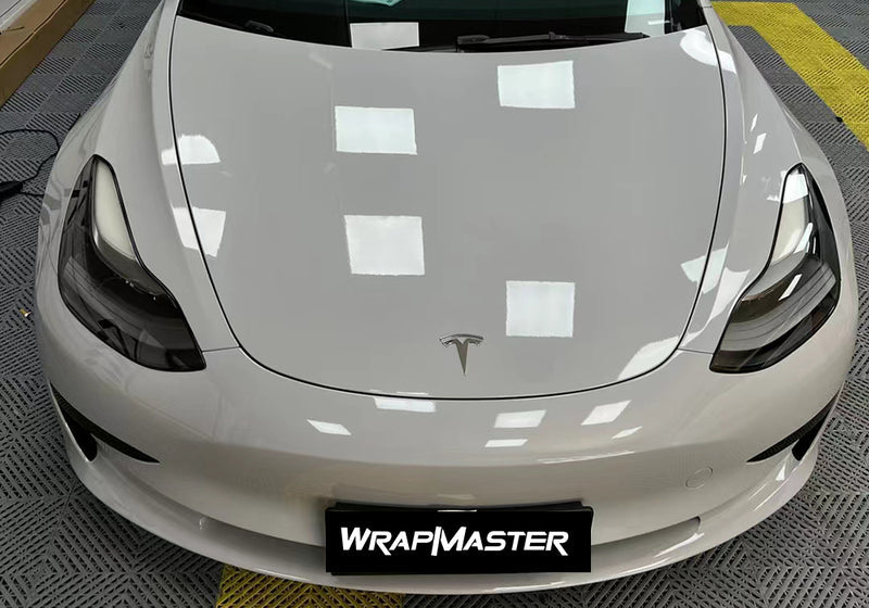 Tesla Model 3 hood and front bumper wrapped in Nardo Gray Super Gloss vinyl under shop lights