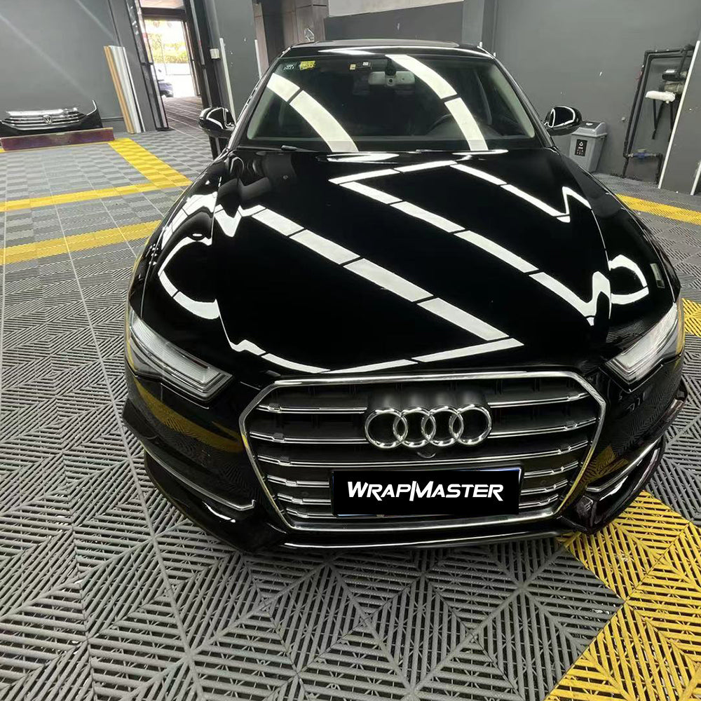 Audi sedan hood and front end wrapped in Black Super Gloss piano black vinyl in a wrap shop