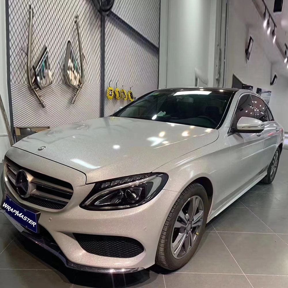 Mercedes-Benz C-Class sedan wrapped in Sparkle Pearlescent White vinyl inside a showroom