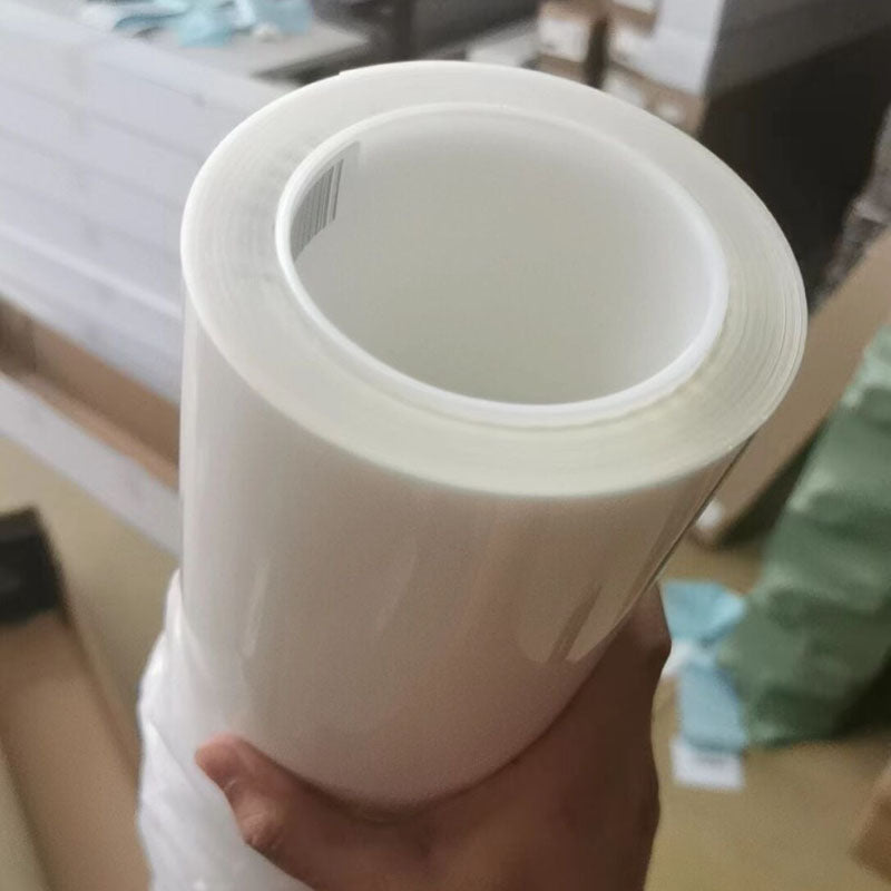Hand holding a roll of clear TPU paint protection film, the film Wrapteck sells as Clear Gloss PPF