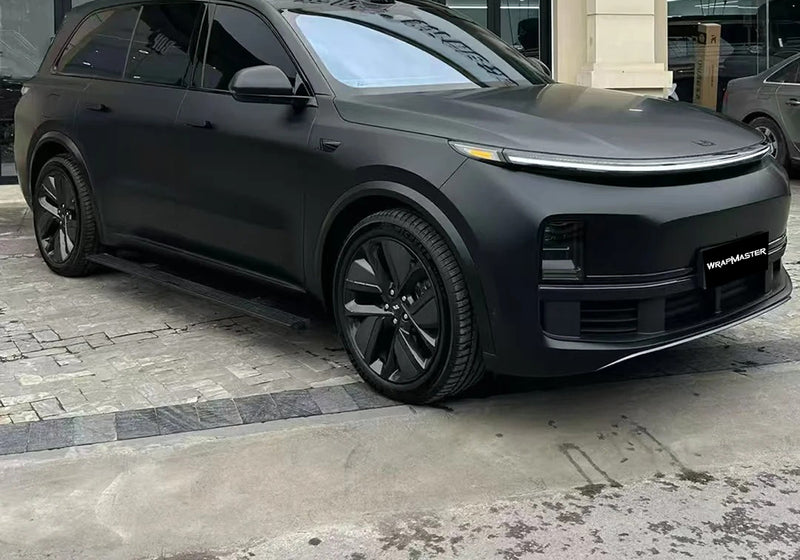 SUV covered in Matte Black color PPF parked on a paved lot outside a glass storefront