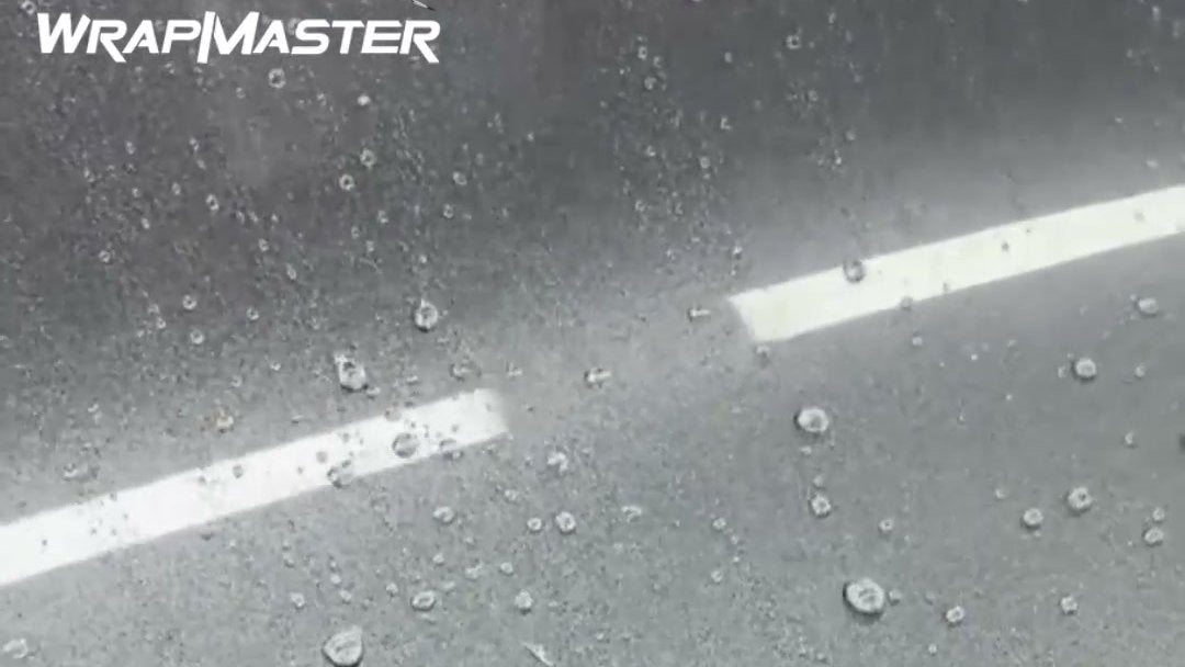 Water beading on TPU paint protection film during a hydrophobic test, WrapMaster logo top left
